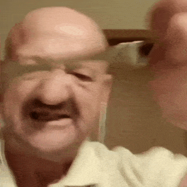 a bald man with a mustache is making a funny face while wearing glasses .