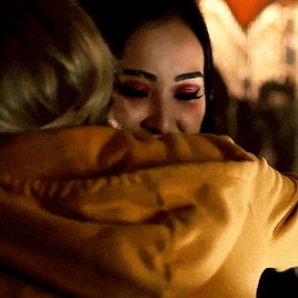 a woman wearing a yellow hoodie with the word vans on the back is hugging another woman