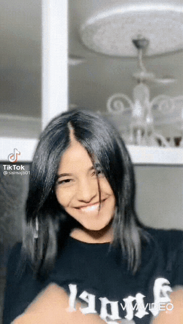a girl with black hair is wearing a black shirt that says angels on it