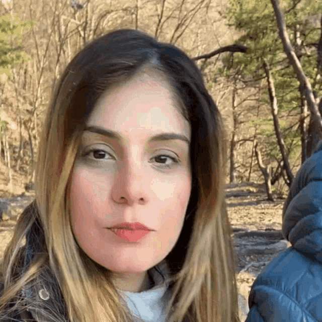 a close up of a woman 's face in front of a forest