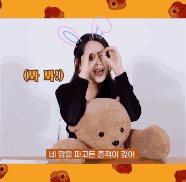 a woman with bunny ears is holding a teddy bear and making a heart with her hands
