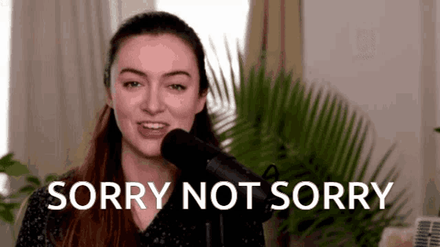 a woman is standing in front of a microphone saying sorry not sorry .
