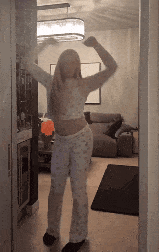 a woman dancing in a living room with a couch in the background