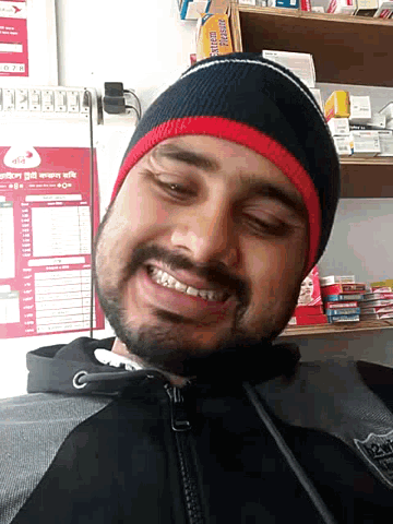 a man wearing a beanie is smiling in front of a shelf with extreme pleasure on it