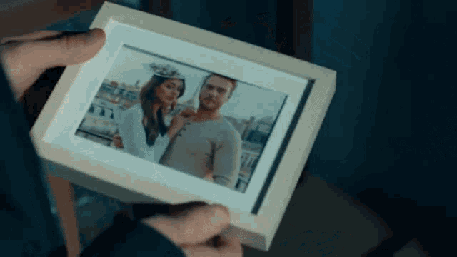 a man is holding a picture of a man and a woman