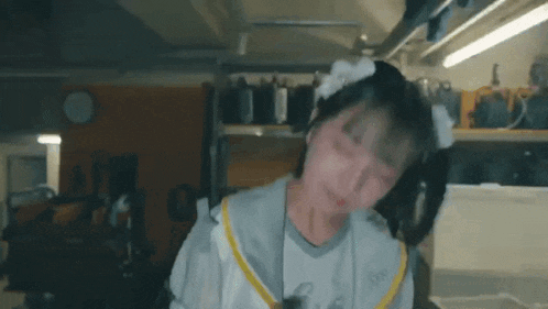 a girl with a bow in her hair is standing in a room with a shelf in the background .