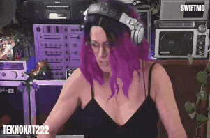 a woman with purple hair wearing headphones and a black tank top with teknokat222 on the bottom