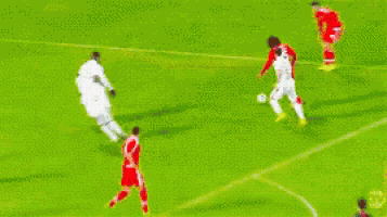 a blurry picture of soccer players on a field with a banner that says ' emirates '