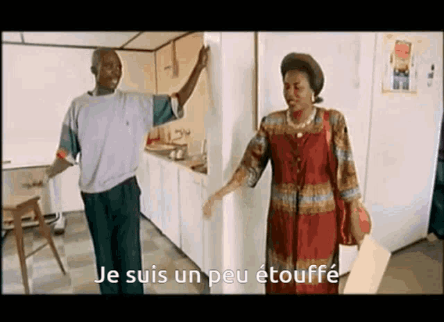 a man and a woman are standing in a kitchen with the words je suis un peu etouffe written on the bottom