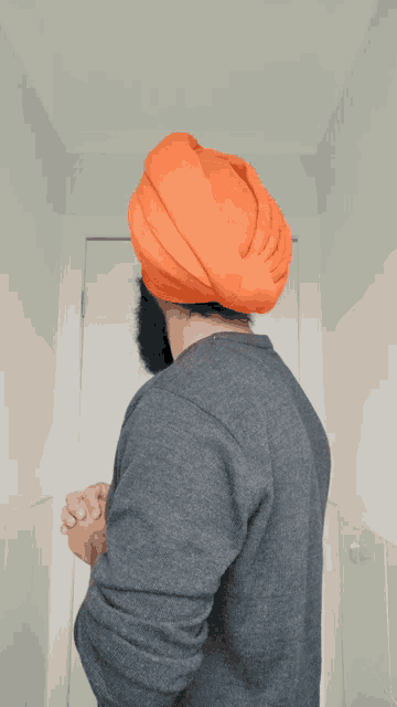 a man with a beard wearing an orange turban and a grey shirt