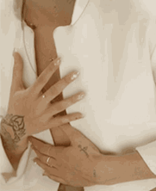 a woman with a tattoo on her hand is holding her chest .
