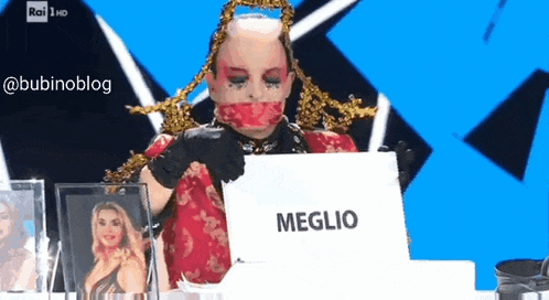 a woman is sitting at a table with a laptop and a sign that says meglio
