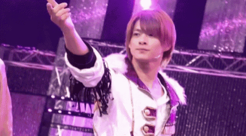a young man in a white and purple outfit is standing on a stage .