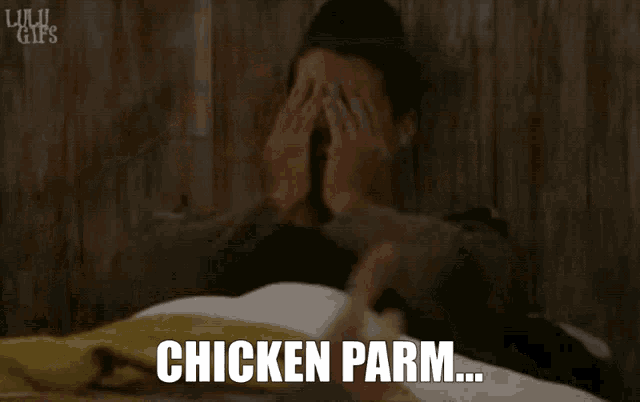 a man laying on a bed with the words chicken parm written on the screen