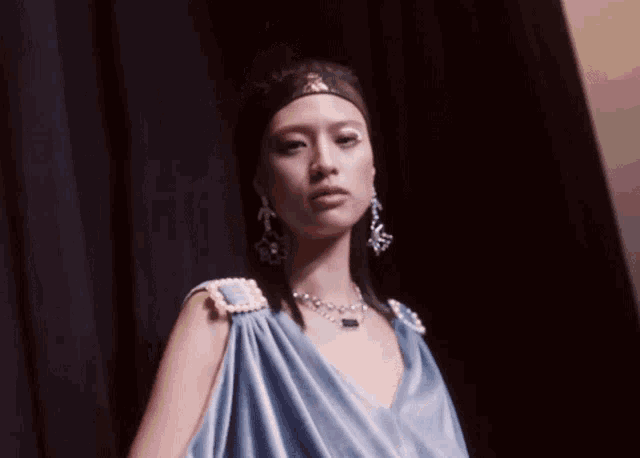 a woman wearing a blue dress with pearls on the shoulders