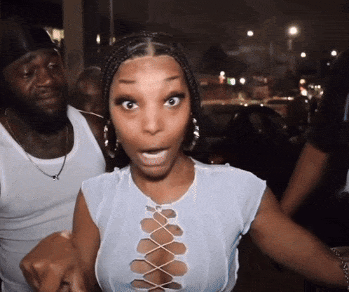 a woman wearing a white lace up top looks surprised