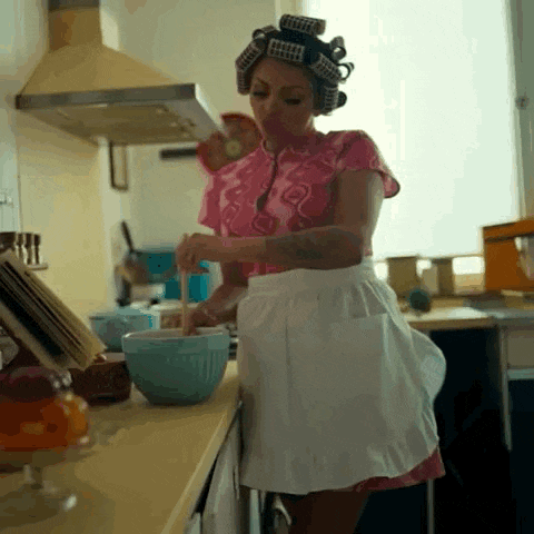 a woman with curlers in her hair is mixing something in a bowl .