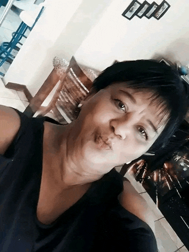 a woman blowing a kiss while taking a selfie in a room