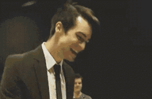 a man in a suit and tie is laughing while holding something