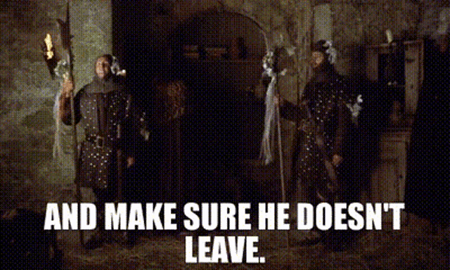 a man in armor is standing next to another man in armor and holding a torch .