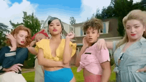 a group of women are standing in front of a house and dancing .