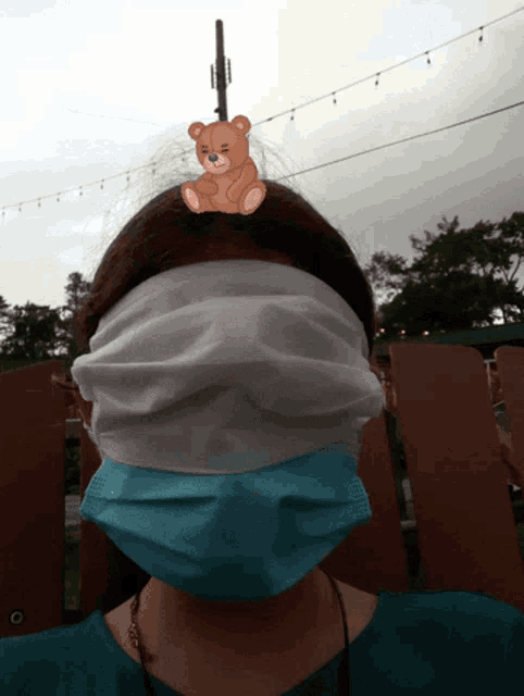a woman wearing a face mask has a teddy bear sticker on her head