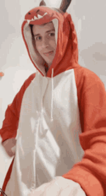 a man is wearing a red and white dinosaur costume
