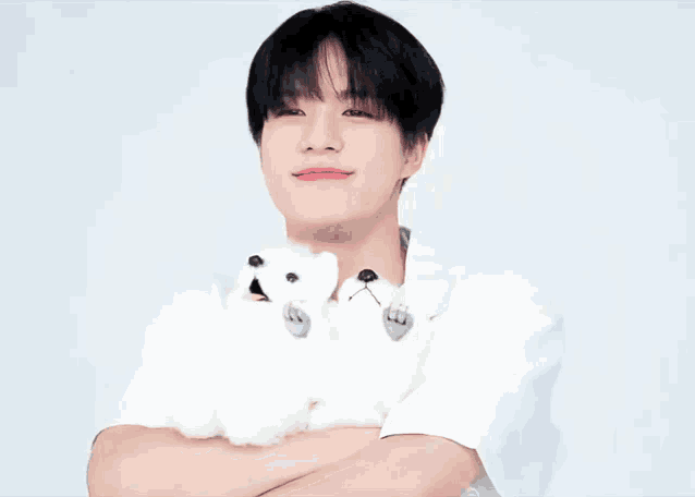 a young man in a white shirt is holding a white stuffed animal .