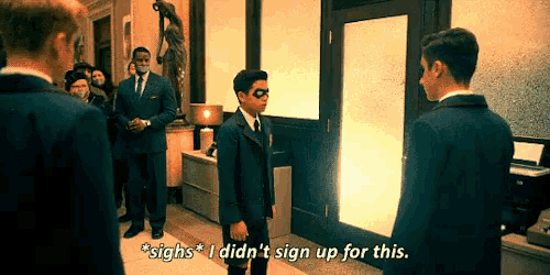 a man in a suit says " sighs i did n't sign up for this " while standing in a hallway