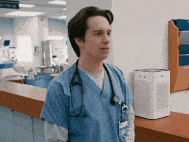 a nurse with a stethoscope around his neck is standing in a hospital