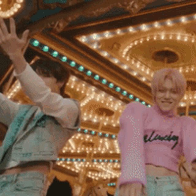 a man and a woman are standing in front of a carousel .