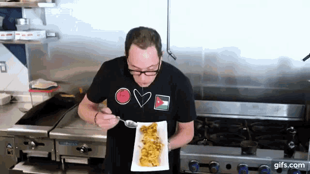 a man in a black shirt that says love is eating food from a plate