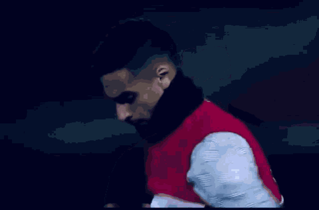 a man with a scarf around his neck is wearing a red vest with the letters ys on it