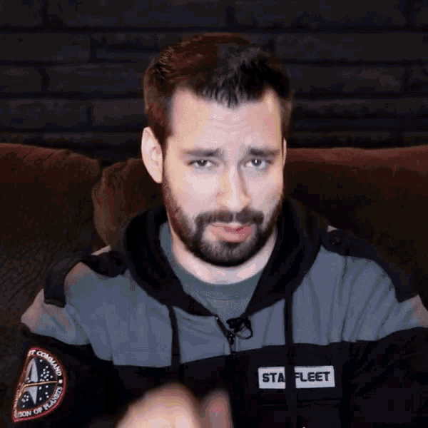 a man with a beard wears a star fleet jacket