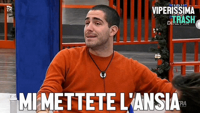 a man wearing an orange sweater says " mi mettete l' ansia "