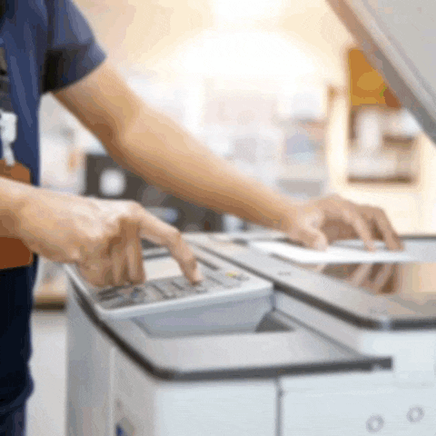 a person is using a copier to scan a document .