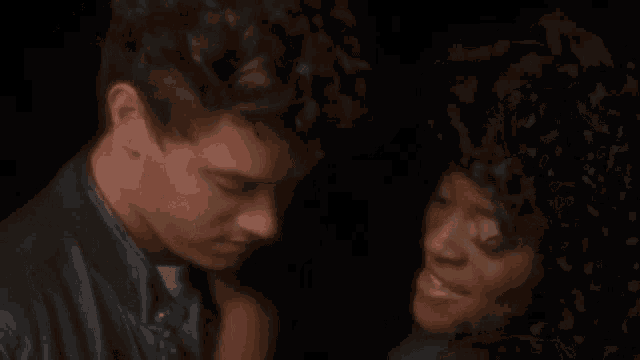 a man and a woman are sitting next to each other in a dark room with their eyes closed .