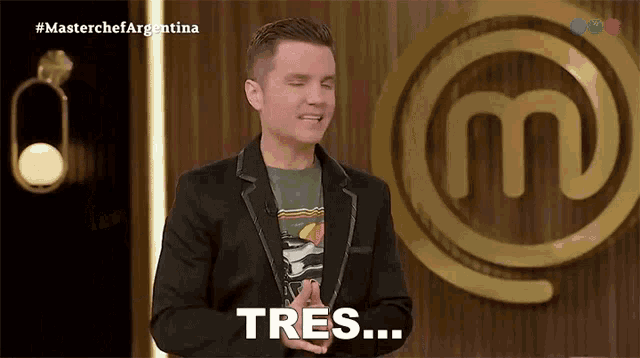a man in a suit stands in front of a masterchef logo