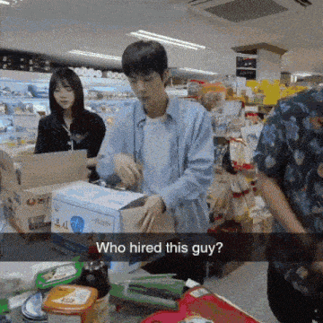 a man in a blue shirt is standing in front of a box that says who hired this guy on it