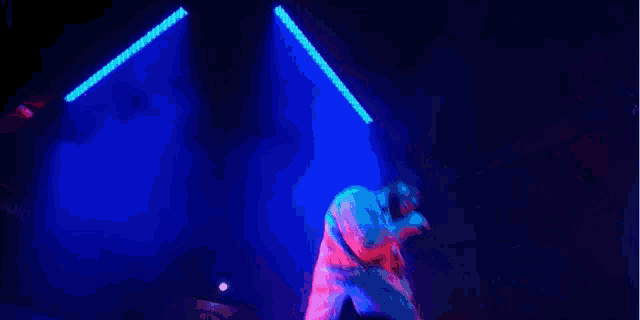 a person is dancing on a stage in a dark room with blue and red lights .