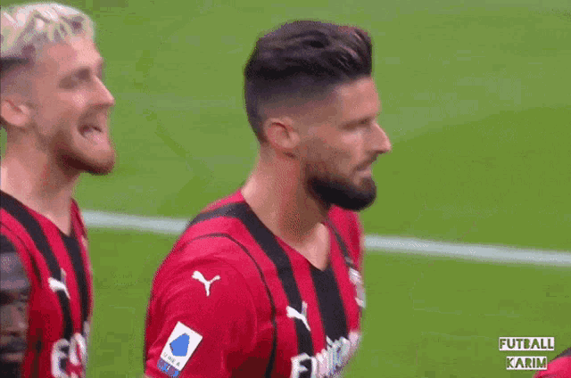 a soccer player wearing a fly emirates jersey stands on the field