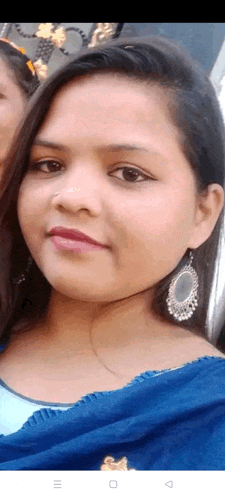 a close up of a woman 's face wearing earrings and a blue top .