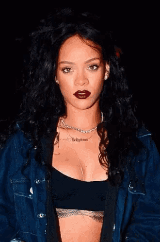 a woman wearing a crop top and a denim jacket has a tattoo on her chest