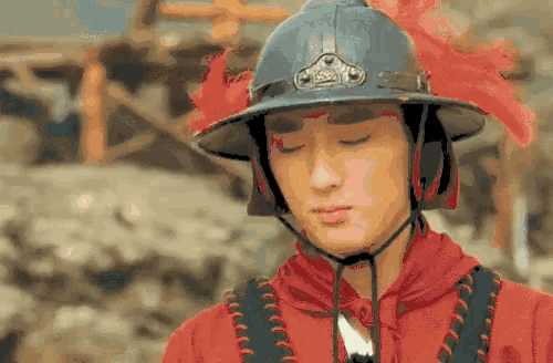 a man wearing a helmet and a red shirt is standing in front of a building .
