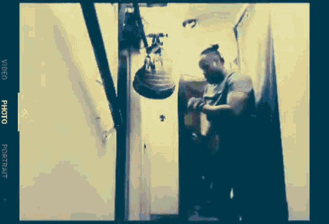 a man is standing in a room with a punching bag hanging on the wall ..