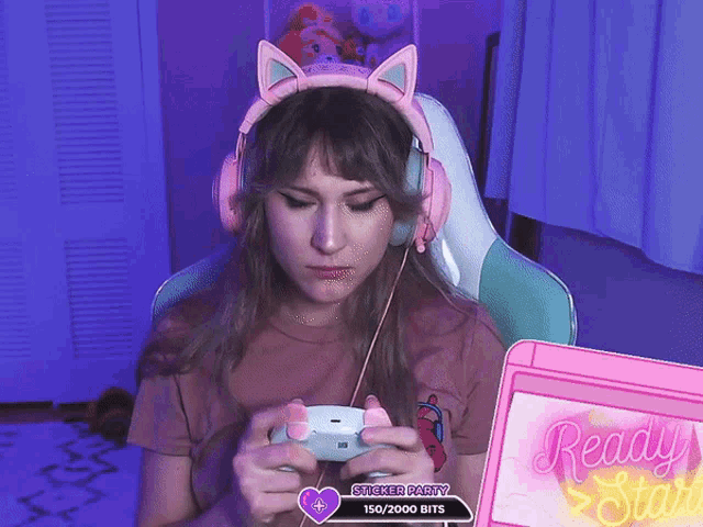 a woman wearing pink headphones is playing a video game with a ready start screen behind her