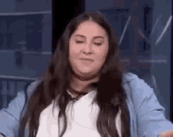 a woman with long hair is making a funny face while sitting in front of a mirror .