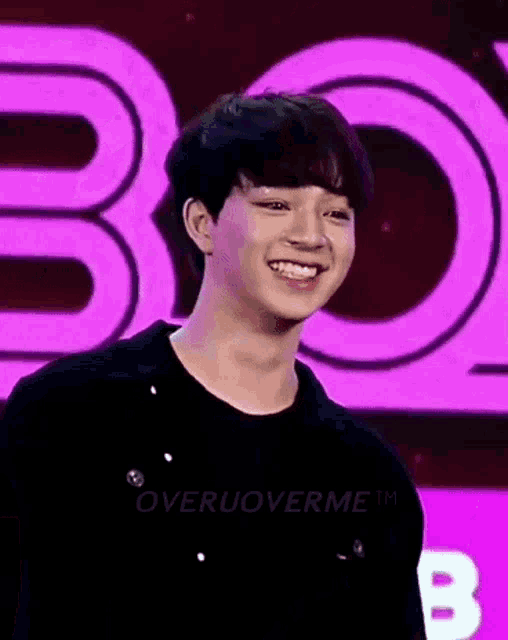 a young man is smiling in front of a purple background .