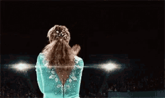 the back of a female gymnast with her arms outstretched .