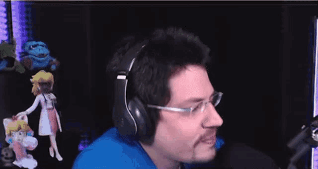 a man wearing headphones and glasses is sitting in front of a microphone in a dark room .